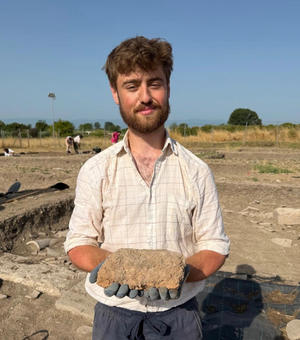 Adam Paterson n a dig holding an item he has excavated